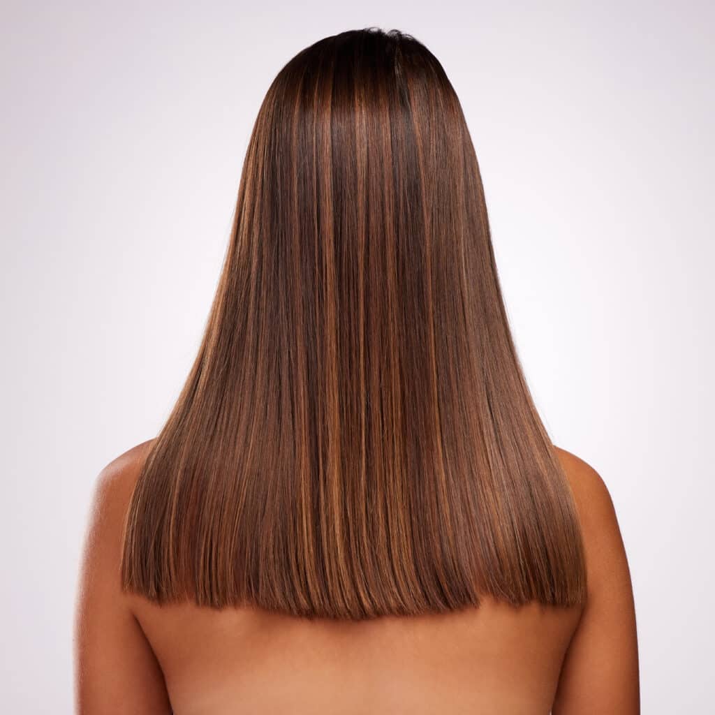 Woman, straight hair and keratin treatment in studio for beauty, cosmetics and white background. Female person, back and balayage for haircare transformation, grooming and color for dermatology